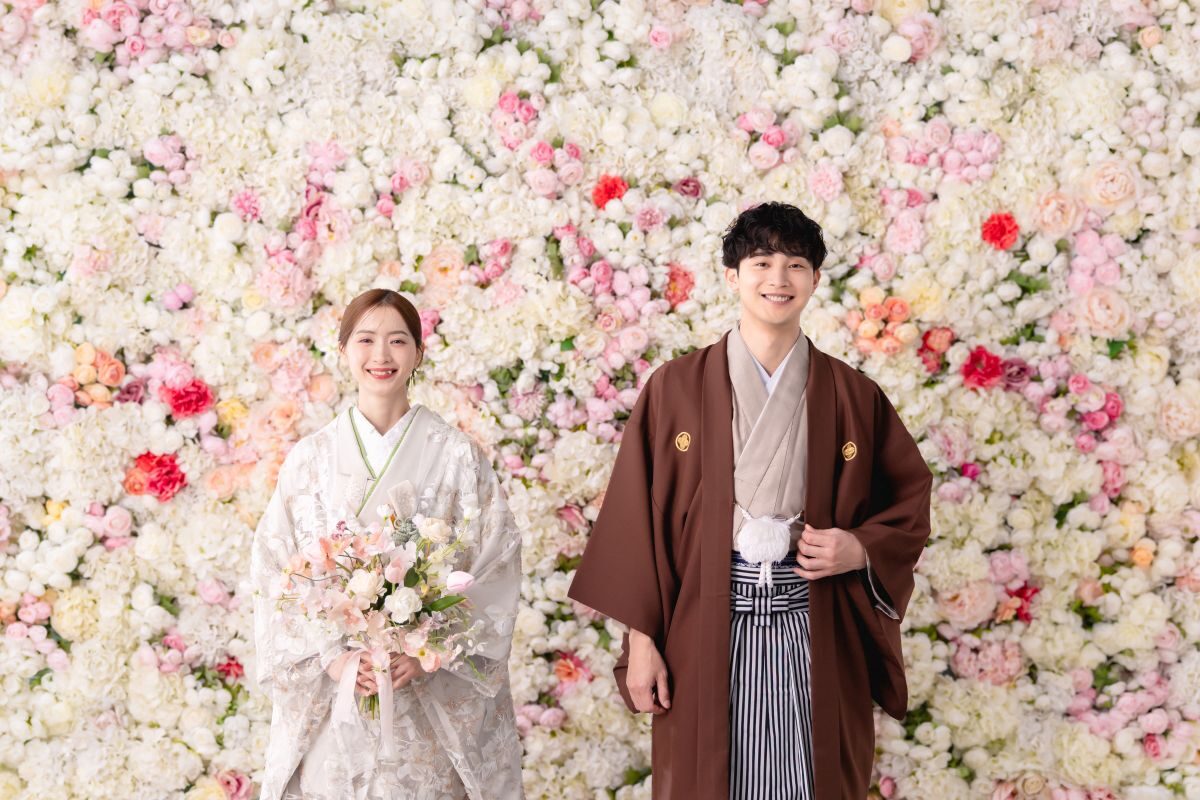 白とピンクの花に囲まれて微笑む和装の新郎新婦